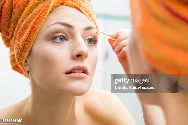 pretty woman plucking her eyebrows - bathroom closeup stock pictures, royalty-free photos & images