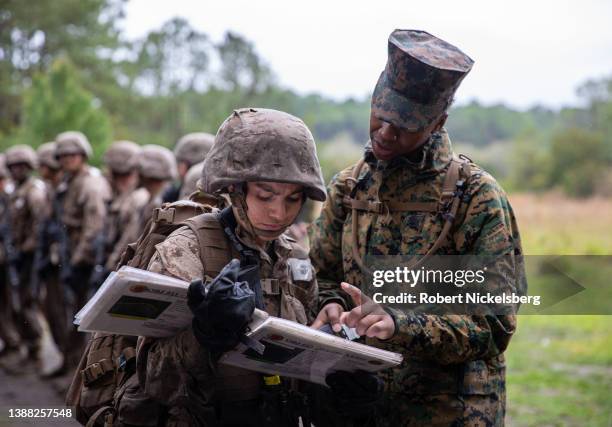 Marine Corps drill instructor shows a female recruit and platoon leader instructions before going through an obstacle course during a Crucible...