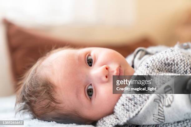 süßer kleiner junge, der auf einem weißen bett liegt - babies only in cloth diapers stock-fotos und bilder