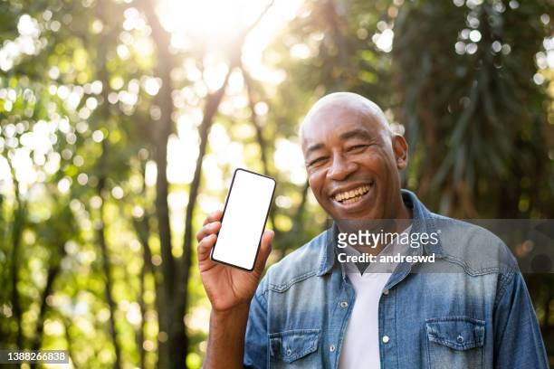 middle-aged man smiling and using cell phone device screen - presenteren stockfoto's en -beelden
