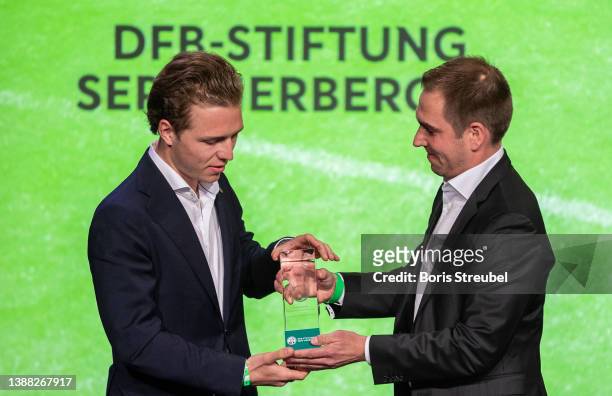 Former football world champion Philipp Lahm hands over a special award to Joel Beckenbauer, representative of the Franz Beckenbauer Stiftung, honored...