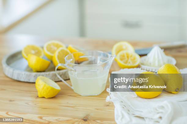 lemon squeezer and lemon juice on kitchen table. - lemon juice stock pictures, royalty-free photos & images