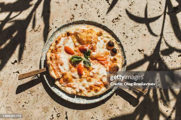 delicious freshly baked margherita pizza on stone table. mediterranean culture - cheese pizza stock-fotos und bilder