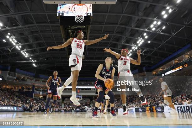 Paige Bueckers of the UConn Huskies looks to shoot the ball while being defended by Kayla Jones and Kai Crutchfield of the NC State Wolfpack in the...