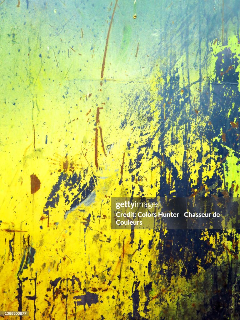 Weathered and rusty metal plate painted yellow and blue in Montreal
