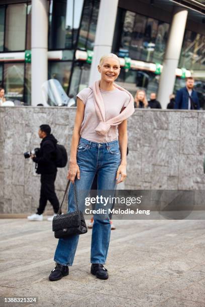 Canadian supermodel Jessica Stam wears a white shirt, pink sweater around her neck, blue jeans, black Chanel bag, and black buckle boots after the...