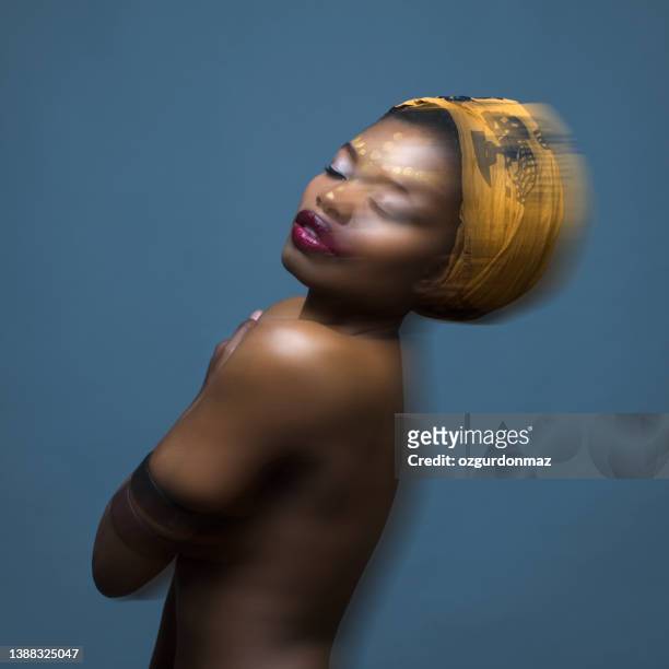 portrait of beautiful african american female wearing a traditional head wrap over isolated gray background - portrait blurred background stockfoto's en -beelden