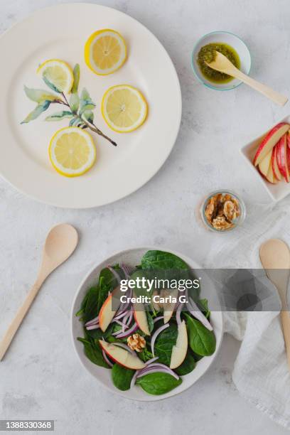 overhead view of spinach salad with red onion, apple, walnuts, lemons. - cutting red onion stock pictures, royalty-free photos & images