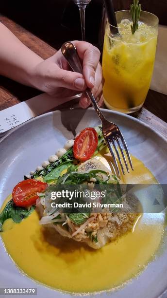 Diner enjoys a dish of pan fried fish of the day in a Laska broth with smoked ginger and cashew puree and a Thai-style salad at chef Luke Dale...