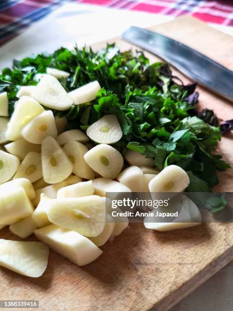close-up of fresh herbs and chopped garlic on old wooden board, cooking at home, angle side view - chopping garlic stock pictures, royalty-free photos & images