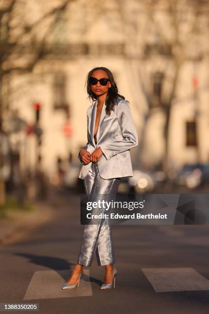 Emilie Joseph @in_fashionwetrust wears black sunglasses, rhinestones earrings, a silver shiny satin with embroidered gold floral jacquard pattern...