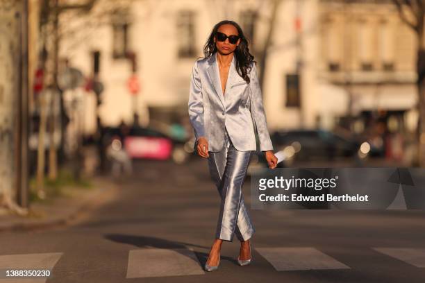 Emilie Joseph @in_fashionwetrust wears black sunglasses, rhinestones earrings, a silver shiny satin with embroidered gold floral jacquard pattern...