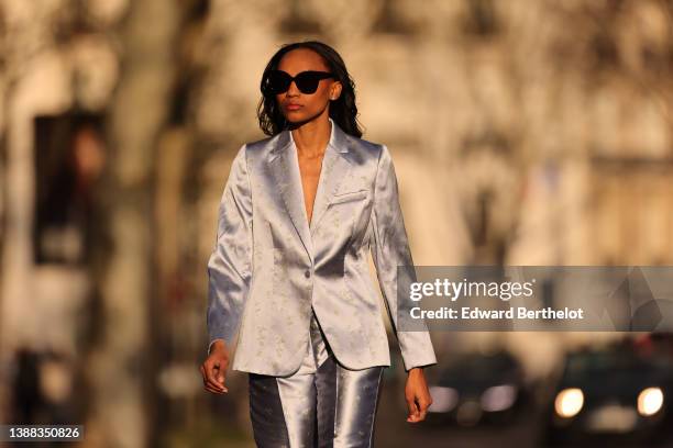 Emilie Joseph @in_fashionwetrust wears black sunglasses, rhinestones earrings, a silver shiny satin with embroidered gold floral jacquard pattern...