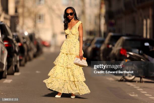 Emilie Joseph @in_fashionwetrust wears black sunglasses, a pale yellow with green and yellow flower print pattern V-neck / tank-top / backless /...