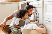 Son helping dad to load washing machine