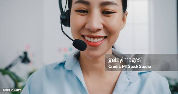 close up of young businesswoman wearing headphones video call via laptop sitting at desk in office. - subcontratação imagens e fotografias de stock