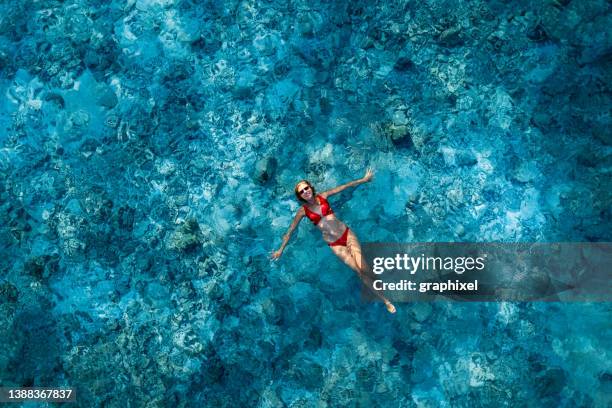 woman lying on crystal water over reef in ocean - white bay stock pictures, royalty-free photos & images