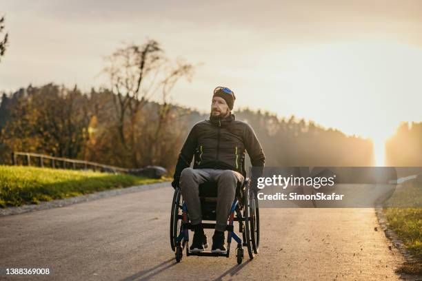 disabled man in wheelchair on road - paraplégico imagens e fotografias de stock