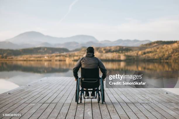 disabled man in wheelchair admiring nature from pier - paraplegic stock pictures, royalty-free photos & images