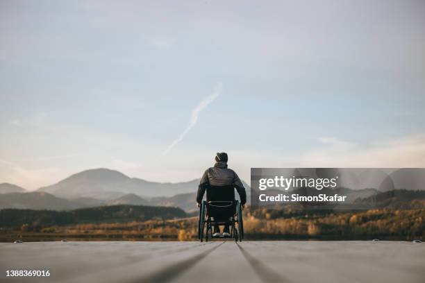 querschnittsgelähmte im rollstuhl am pier bei sonnenuntergang - man in wheelchair stock-fotos und bilder