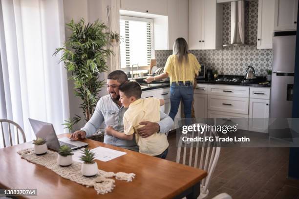 man being embraced by son while working from home - returning computer stock pictures, royalty-free photos & images