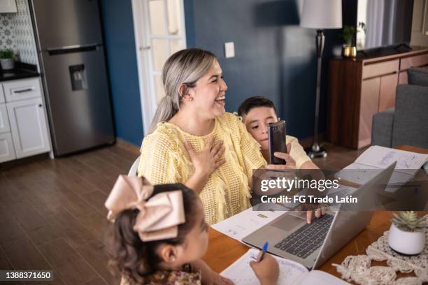 woman and kids doing a video call on smartphone at home - friends laughing at iphone video stock pictures, royalty-free photos & images