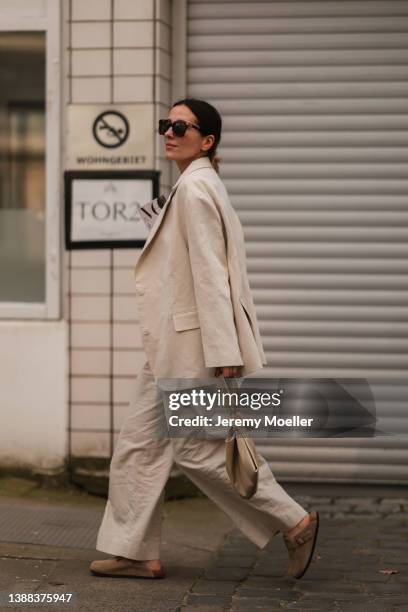 Elise Seitz is seen wearing a COS beige linen pants, H&M beige top, Nanushka beige leather bag, Soho Studios beige linen blazer, Bottega Veneta Brown...