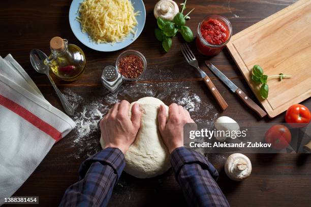 cooking italian vegetarian pizza with vegetables and mushrooms at home, pizzeria or cafe. a woman baker, pastry chef or cook kneads and rolls the dough with her hands, in a bakery. the concept of food. step-by-step instructions, do it yourself. step 1. - vegetarian pizza stock pictures, royalty-free photos & images