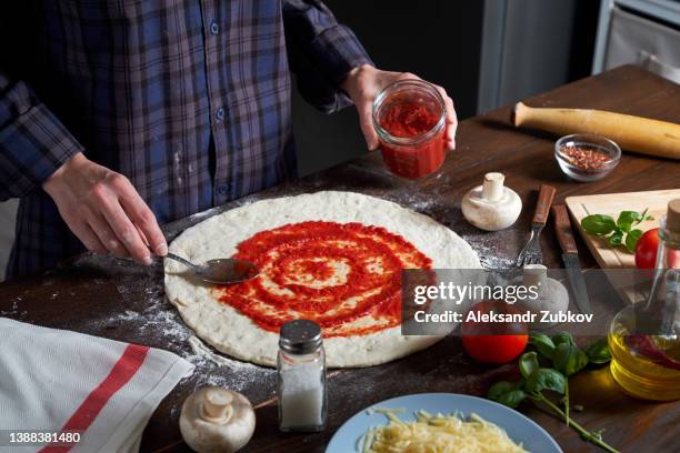 cooking italian vegetarian pizza with vegetables and mushrooms at home, pizzeria or cafe. a woman baker, pastry chef or cook spreads ketchup with a spoon on the dough, in a bakery. the concept of food. step-by-step instructions, do it yourself. step 1. - pizza ingredients stock pictures, royalty-free photos & images