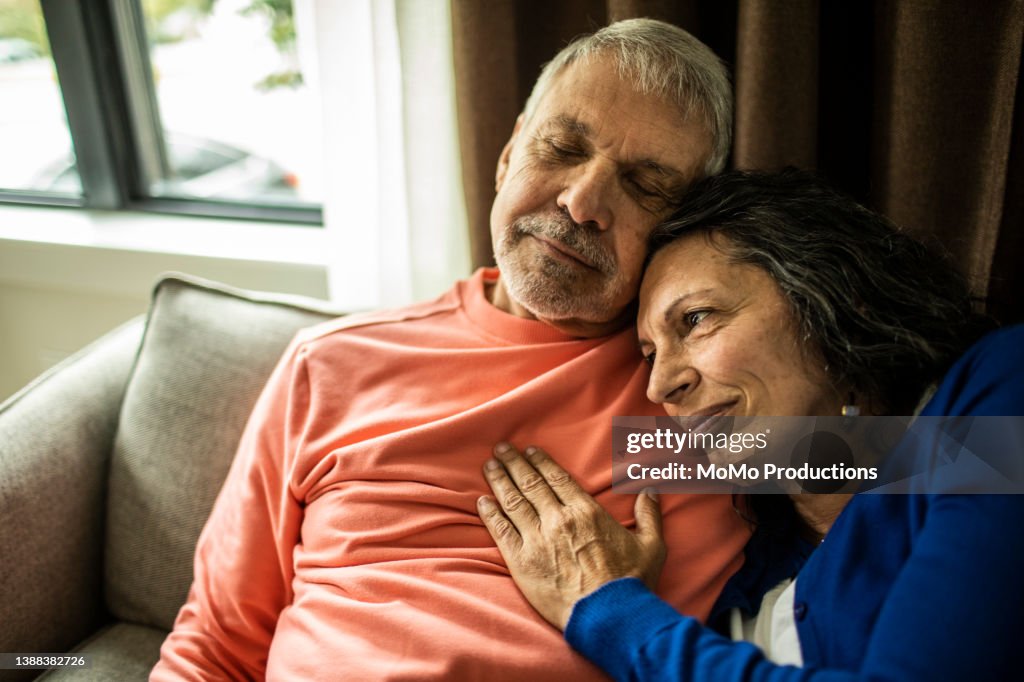 Senior couple cuddling on couch at home