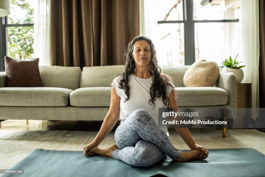 Senior woman doing yoga inside home