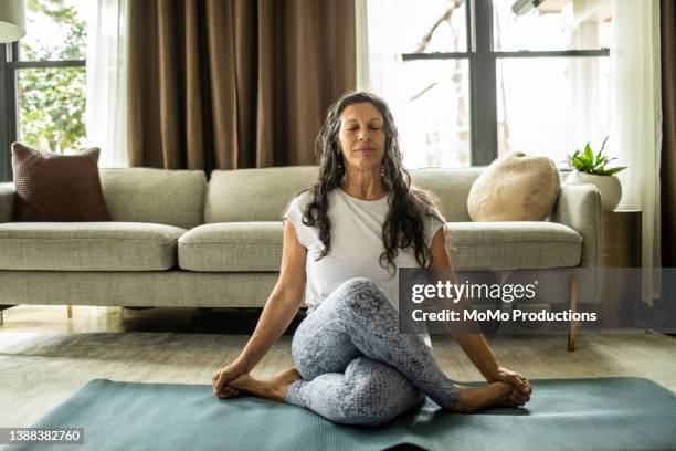 senior woman doing yoga inside home - active senior woman imagens e fotografias de stock