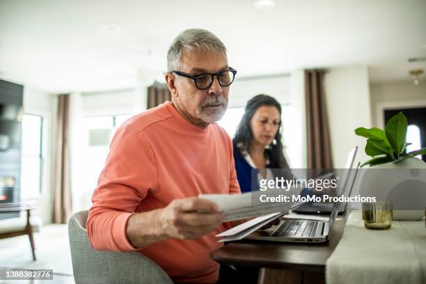 senior couple payings bills inside home - home finances man stock pictures, royalty-free photos & images