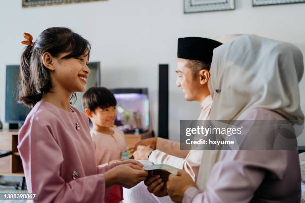 malay muslim children in traditional clothings received gift of money from their parents during hari raya aidilfitri celebration - ramadan giving stockfoto's en -beelden