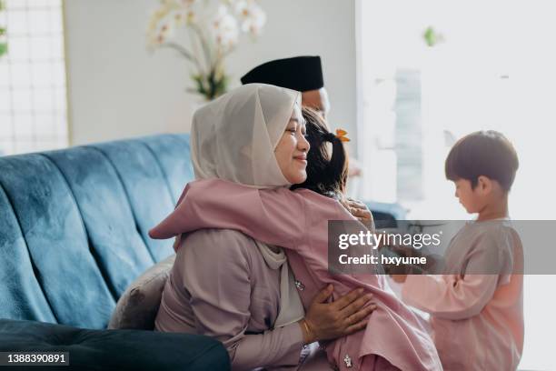 malay muslim woman in traditional clothings hugging her daughter during hari raya aidilfitri celebration - eid greeting stock pictures, royalty-free photos & images