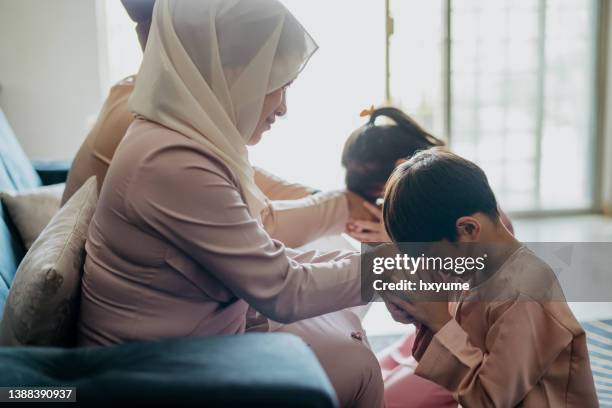 malay muslim children in traditional clothings asking forgiveness to their parents during hari raya aidilfitri celebration - kyssa på handen bildbanksfoton och bilder