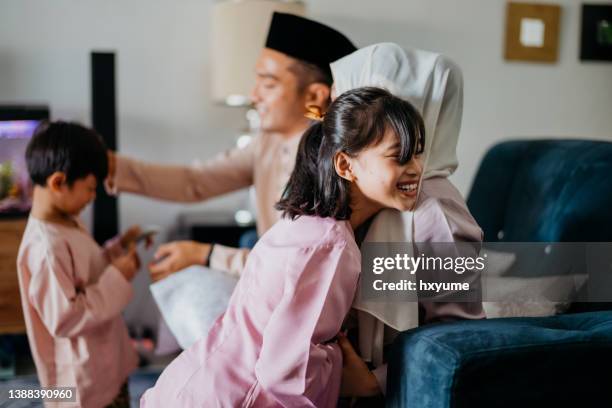 malaiisch-muslimische kinder in traditioneller kleidung bitten ihre eltern während der hari raya aidilfitri-feier um vergebung - hari raya celebration stock-fotos und bilder