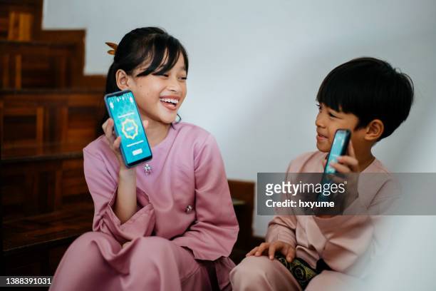 young muslim children in receive digital gift of money sent via smartphone - heritage festival presented stock pictures, royalty-free photos & images
