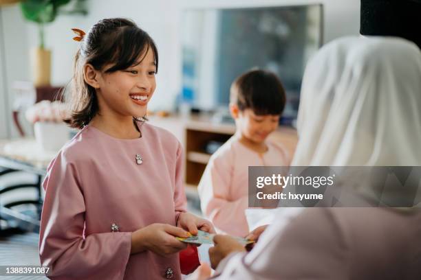 malay muslim children in traditional clothings received gift of money from their parents during hari raya aidilfitri celebration - ramadan giving imagens e fotografias de stock