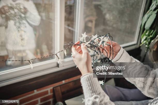 woman trying to untangle christmas lights - tangled christmas lights stock pictures, royalty-free photos & images