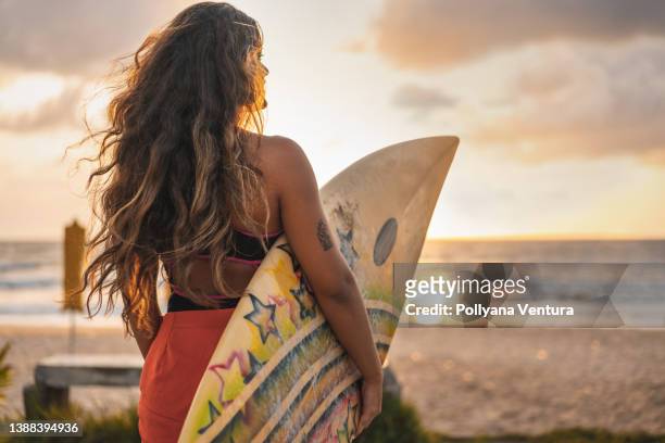 woman holding surfboard looking at the sea - wavy hair stockfoto's en -beelden