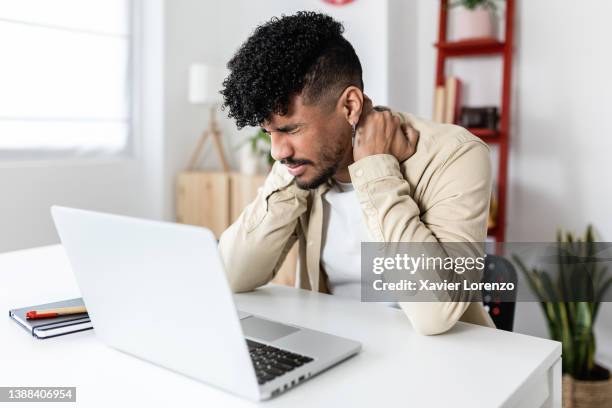 exhausted young hispanic latino man having a stressful time while working from home. - venezuelans stock pictures, royalty-free photos & images