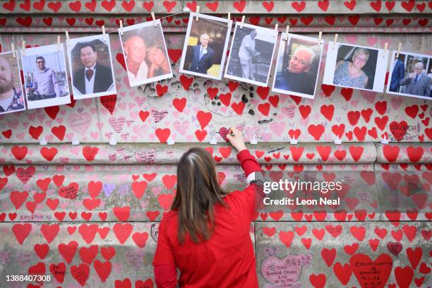 Woman leaves a message below photos of some of those who died during the Covid-19 pandemic, on the first anniversary of the creation of the Covid...