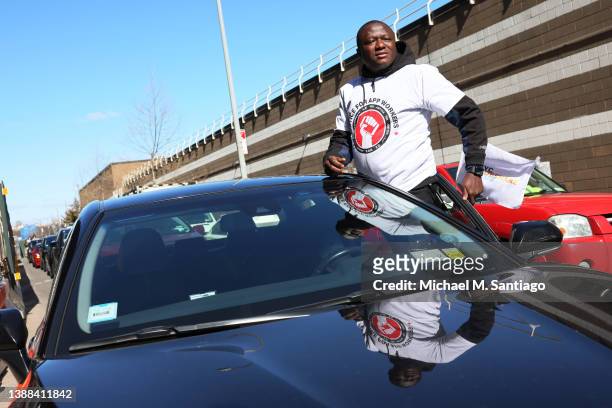 Mohammed Dukuly, a Lyft driver, hangs out of his car as he joins other app-based drivers and delivery workers take part in a protest at the former...