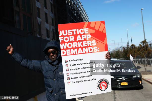 Aziz Bah, an Uber and Lyft driver and organizer of the protest, walks as he carries a sign as he joins other app-based drivers and delivery workers...