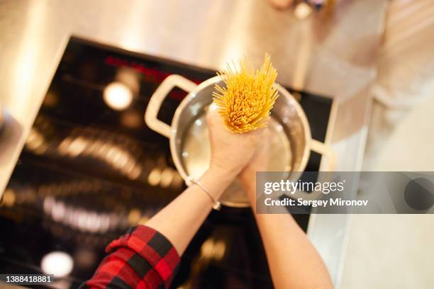 crop woman cooking pasta in pan in kitchen - one pot pasta stock-fotos und bilder