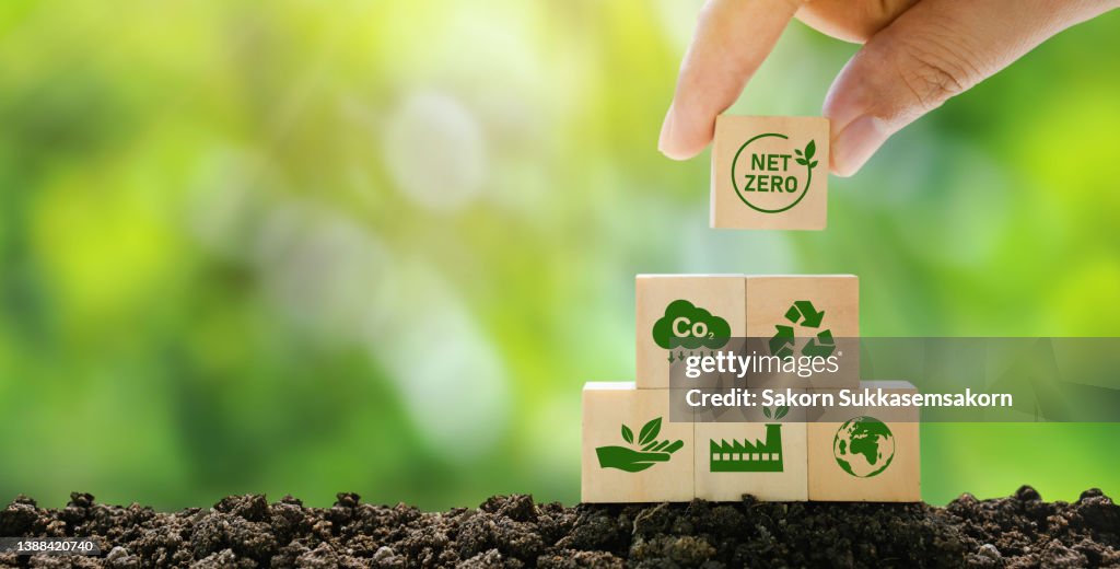 Net Zero und Klimaneutrale Konzepte Netto-Null-Emissionsziele Eine klimaneutrale Langzeitstrategie Bereit, Holzblöcke von Hand mit grünem Net-Center-Symbol und grünem Symbol auf grauem Hintergrund zu platzieren.