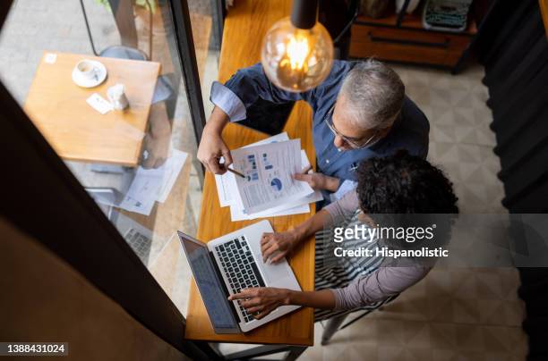 business owner and manager working on the finances of the shop using a laptop - fintech imagens e fotografias de stock