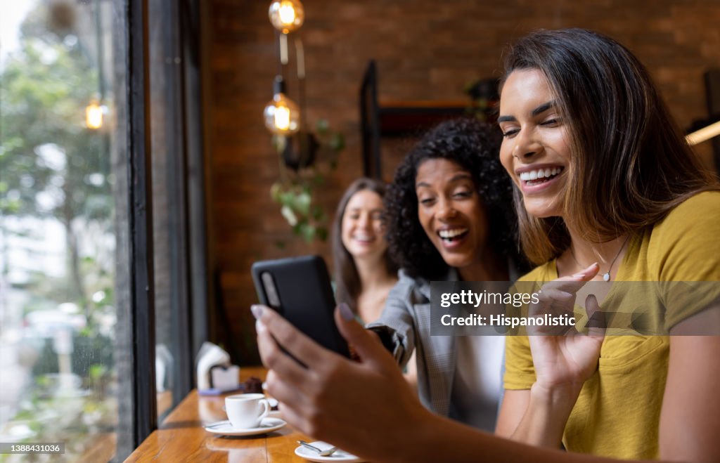 Gruppe von Freunden in einem Café, die social media auf einem Handy betrachten
