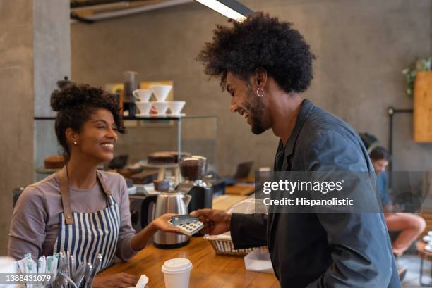 man making a contactless payment at a cafe - card reader stockfoto's en -beelden